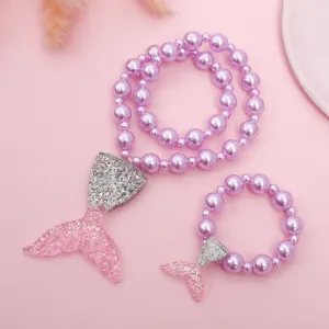 Detailed shot of kids mermaid tail pearl necklace and bracelet set with glitter resin charms.