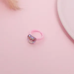 Detailed shot of a cute pink children's ring featuring a sparkling mermaid scale heart pendant.