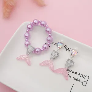 Children resin mermaid tail jewelry set detail, purple beaded bracelet and pink earrings.