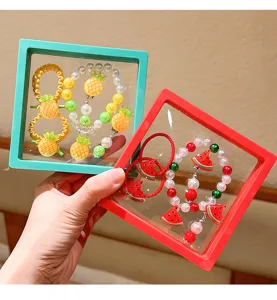 Close-up of children fruit theme pearl bracelet and hair tie set in transparent frame.