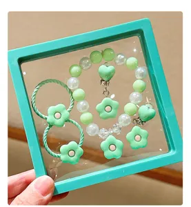 Close-up detail of children green flower pearl bracelet and hair accessories set in box.