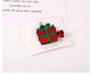 Close-up detail shot of the sparkling red and green glitter gift box hair clip on card.