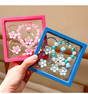 Detailed shot of kids flower pearl bracelet and hair tie gift box set in pink and blue.