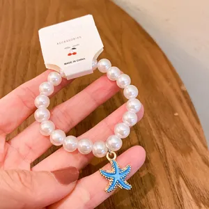 Detailed view of the cute pearl bracelet with blue starfish pendant charm closeup shot.