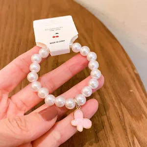 Close-up detail of pearl beaded bracelet with cute pink butterfly charm and hanging tag.