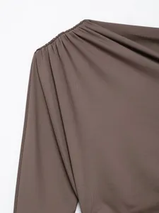 Brown stretchy asymmetric top shoulder detail, pleated long sleeve fashion apparel closeup.