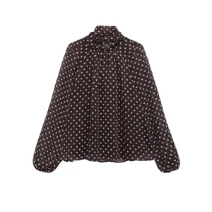 Detailed view of the sheer polka dot fabric and elegant high collar design of the blouse.