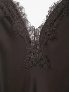 Detailed view of women's V-neck slip dress with delicate lace trim on smooth satin fabric.