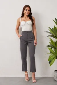 Detailed shot of woman wearing high-waist grey suit trousers and chic white chain top.