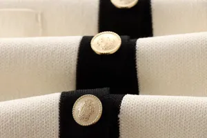 Nahaufnahme des Damen Kontrast Strickoberteils mit goldenen Knöpfen und schwarzem Rand.