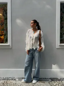 Detailed view of a chic white ruffled V-neck long sleeve blouse paired with wide leg jeans.