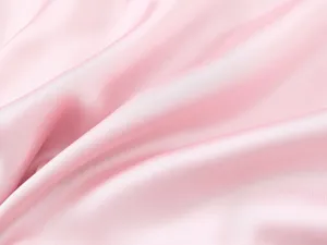 Gros plan de tissu satiné rose, texture lisse et éclat élégant pour robe élégante.