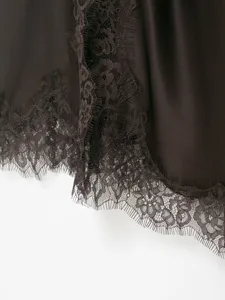 Close-up detail of dark satin slip dress featuring delicate floral lace trim along hem edge.