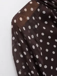 Close-up view of elegant brown chiffon fabric featuring classic white polka dots and texture.