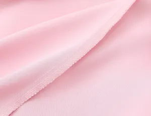 Détail du tissu de la robe rose en gros-plan, montrant une texture satinée et des coutures.