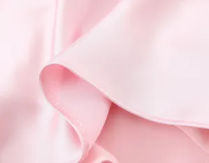 Gros plan sur le tissu de robe en satin rose montrant une texture brillante et des coutures.