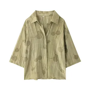 Détails en gros plan de la chemise vert clair avec imprimé floral et texture plissée.