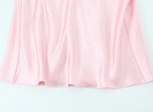 Gros plan de l'ourlet de robe en satin rose, drapé lisse et détail de tissu brillant élégant.