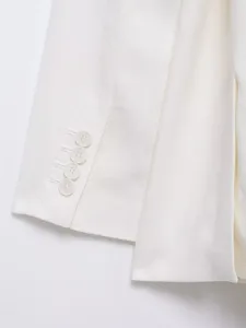 Vue rapprochée d'un manchon de blazer en lin blanc avec de jolis boutons assortis.