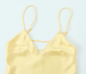 Gros plan de robe nuisette en satin jaune, élégant design à bretelles fines.