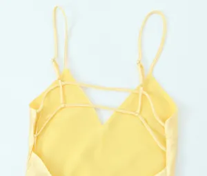 Détail de robe en satin jaune, bretelles fines ajustables et dos croisé élégant.