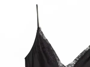 Close-up of a black satin camisole dress with delicate lace trim and thin straps.