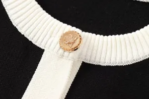 Nahaufnahme Detail des schwarz-weißen Damen Strickoberteils mit goldenen Knöpfen.