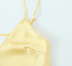 Détail de robe nuisette en satin de soie jaune, texture bretelle fine sans manches, tissu.