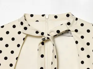 Elegantes Polka-Dot-Kleidungsdetail mit schickem Schleifenkragen und Reißverschluss hinten.