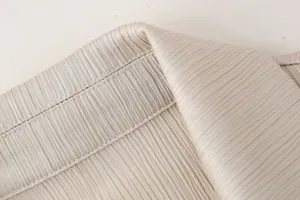 Vista detallada de la textura de tela plisada y costuras limpias en prenda de moda femenina.