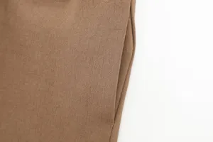 Close up detail view of brown trousers fabric, soft texture, clean white background.