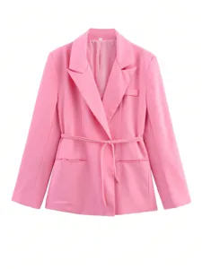 Détail de blazer rose avec élégant col à revers, manches longues, fine ceinture et poche.