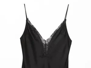 Black satin slip dress detail, featuring delicate V-neck lace trim and thin adjustable straps.