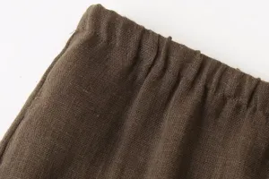 Brown linen fabric detail close-up showing fine texture and elastic waistband design.