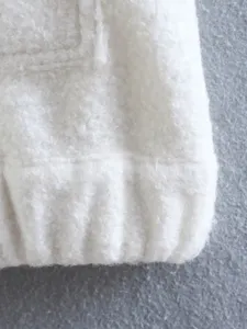 Close-up detail of white fuzzy fleece jacket hem showing soft fluffy texture and ribbing.
