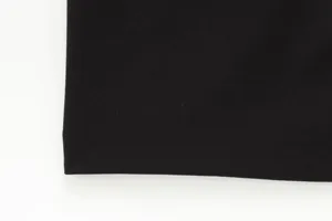 Detailed view of the sleek black fabric and neat hemline of the women's midi dress.