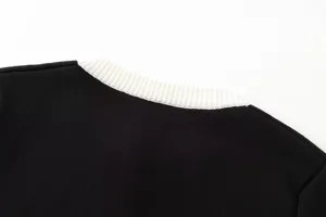 Nahaufnahme der Details eines schwarzen Damen-Strickoberteils mit kontrastierendem weißem Rippkragen.