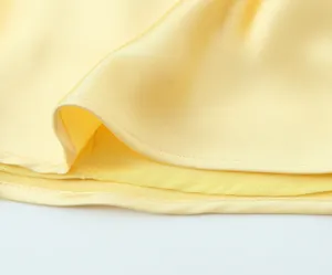 Gros plan détaillé du bord de tissu satiné jaune présentant une texture fine et lisse.