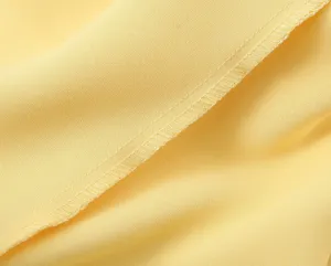 Gros plan sur un tissu en satin de soie jaune lisse avec détail de couture propre.