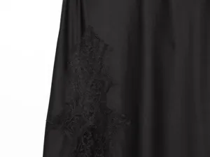 Black satin slip dress detail featuring delicate lace trim, showcasing texture and fine craftsmanship.