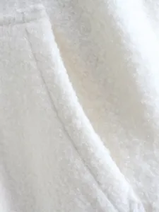 White fleece jacket detail shot showing soft fluffy sherpa fabric texture and neat seams.