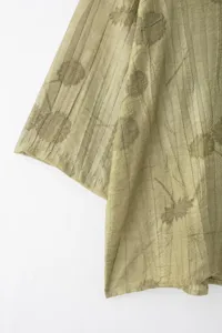 Gros plan détaillé de la chemise plissée vert clair pour femme avec texture unique.
