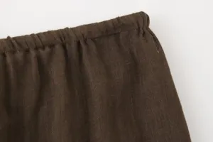 Close-up detail of dark brown linen blend elastic waistband women apparel fabric texture.