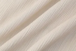 Primer plano detallado de la textura de tela arrugada beige claro, diseño plisado.