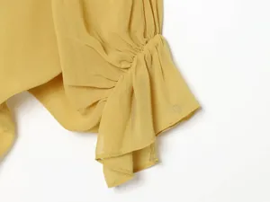 Detailed view of womens yellow chiffon ruffled sleeve with delicate pleats and soft texture.