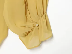 Yellow chiffon blouse sleeve detail, elegant ruched cuff with button accent for summer.