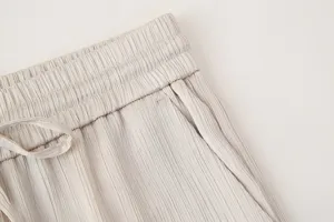 Primer plano detallado de la cintura de un pantalón casual plisado de mujer beige.