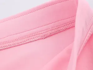 Détails de coutures roses raffinés sur le col et la taille de la veste de sport.