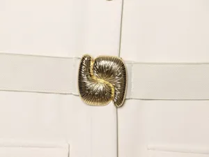 Close-up detail of a chic women's elastic dress belt with a unique gold abstract metal buckle.