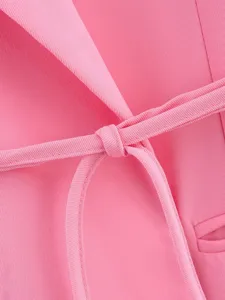 Vue de detail du tissu du blazer rose montrant la texture et le noeud de ceinture
